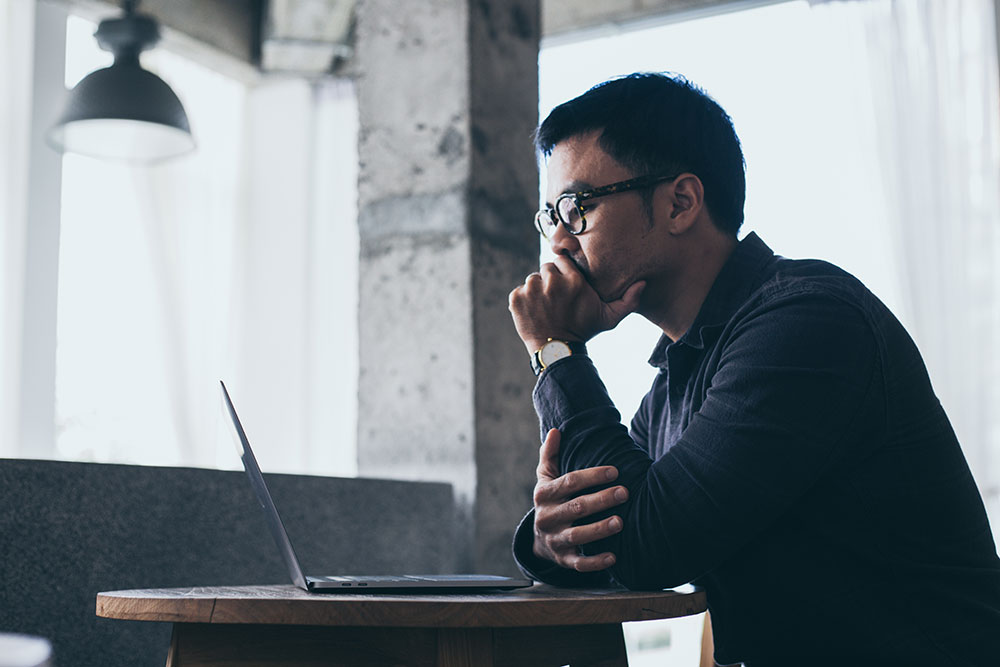 worried man on laptop looking at interest rates